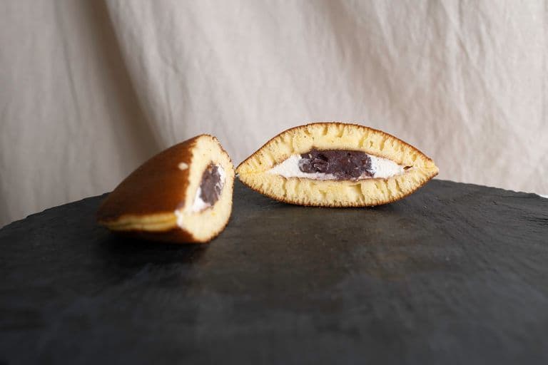 A taiyaki, a fish-shaped Japanese pastry filled with sweet red bean paste, depicted in a cross-section showing the filling.