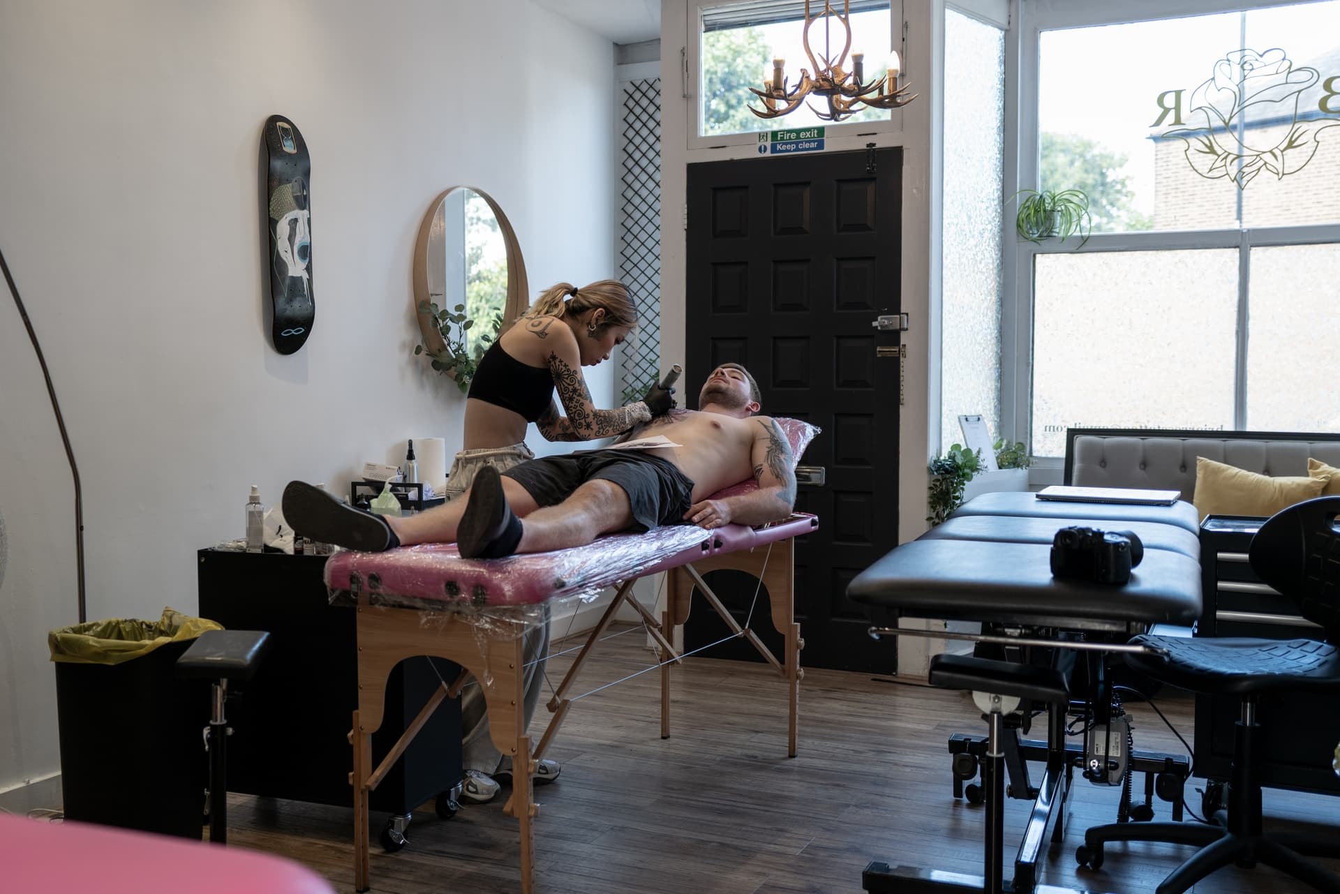 Tattoo artist creating a tattoo on a man's chest in a tattoo studio.
