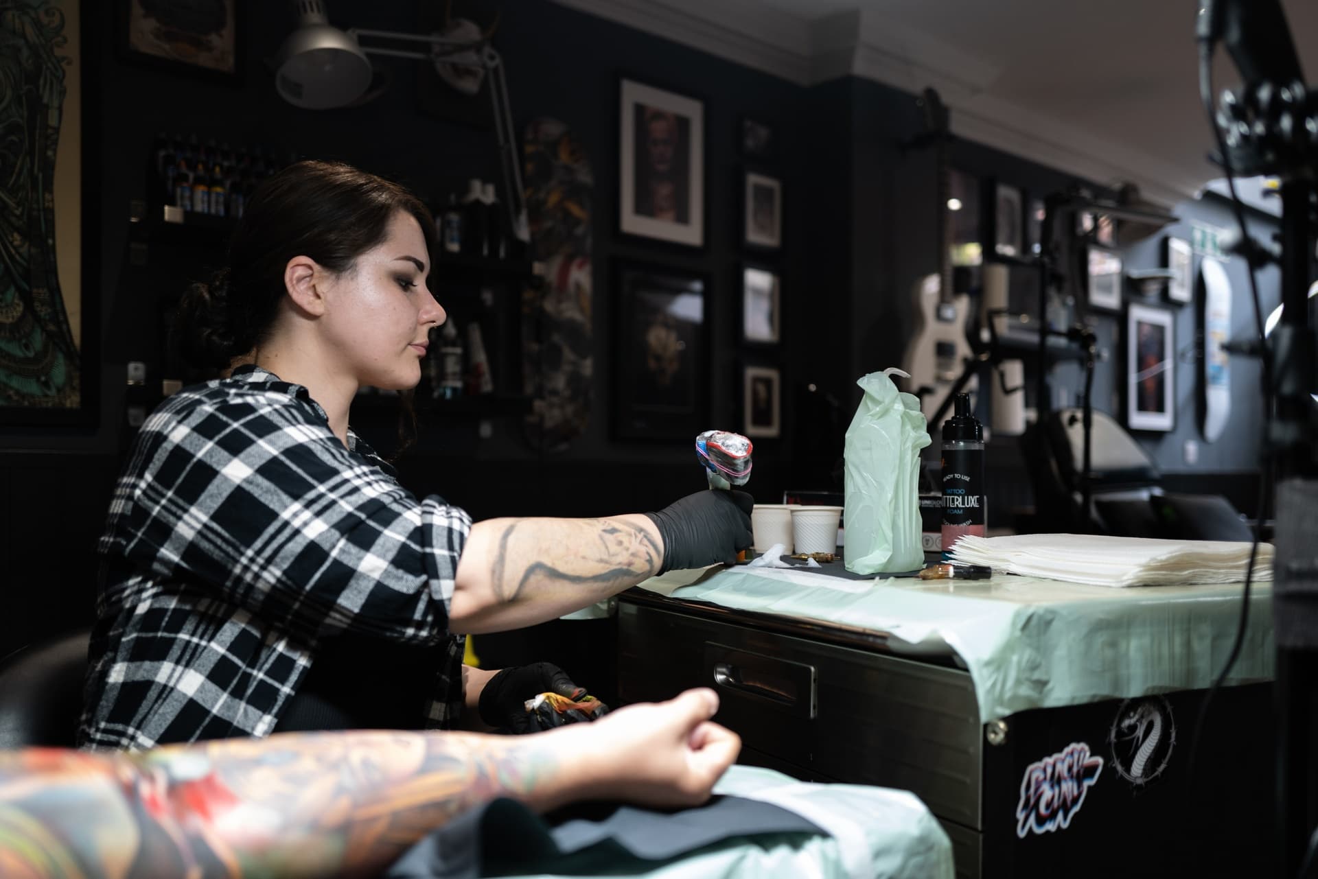 Tattoo artist working on tattoo at a tattoo station with tattoo inks, gloves, and tattoo supplies in a tattoo studio