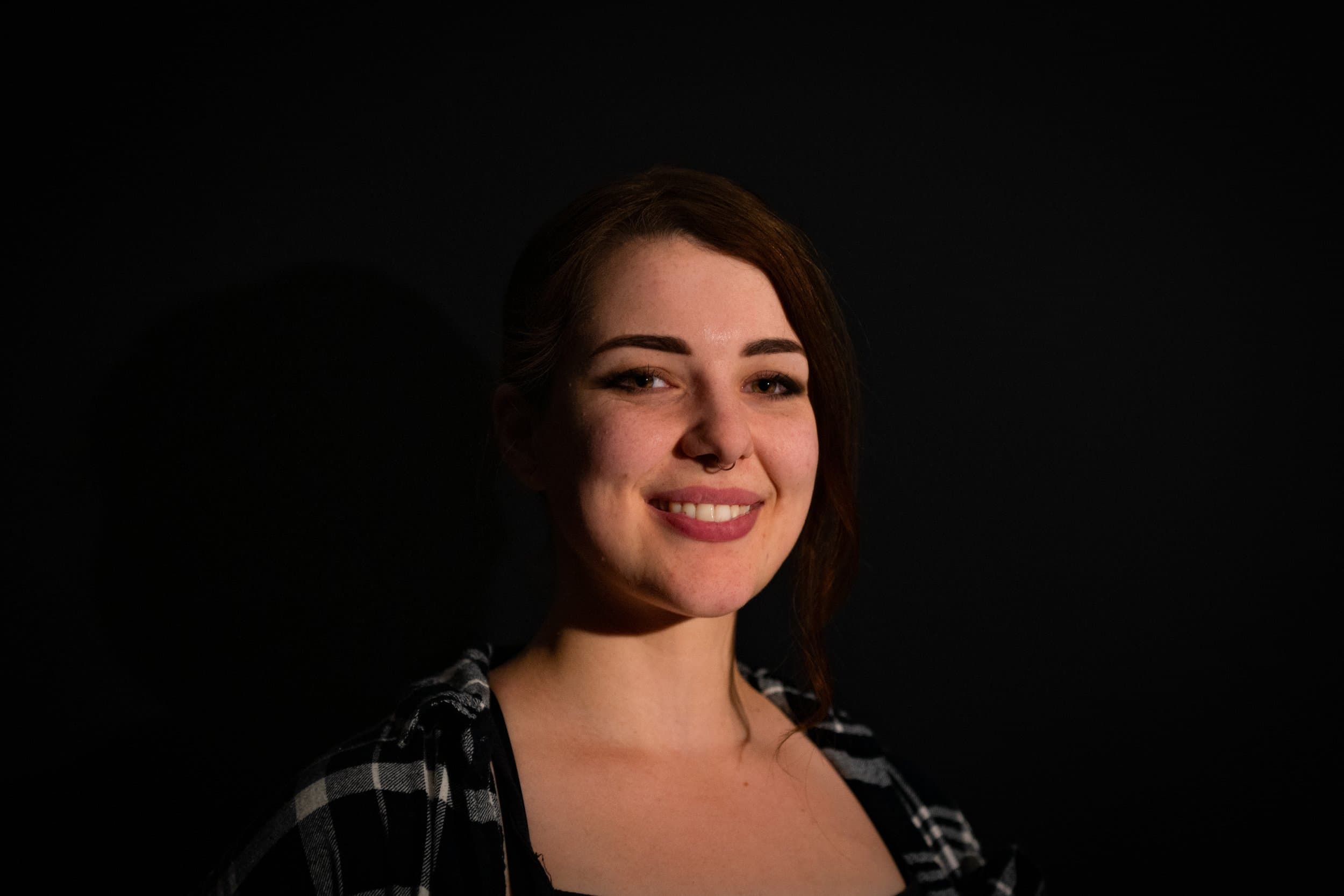 Smiling woman in a dark room with plaid shirt