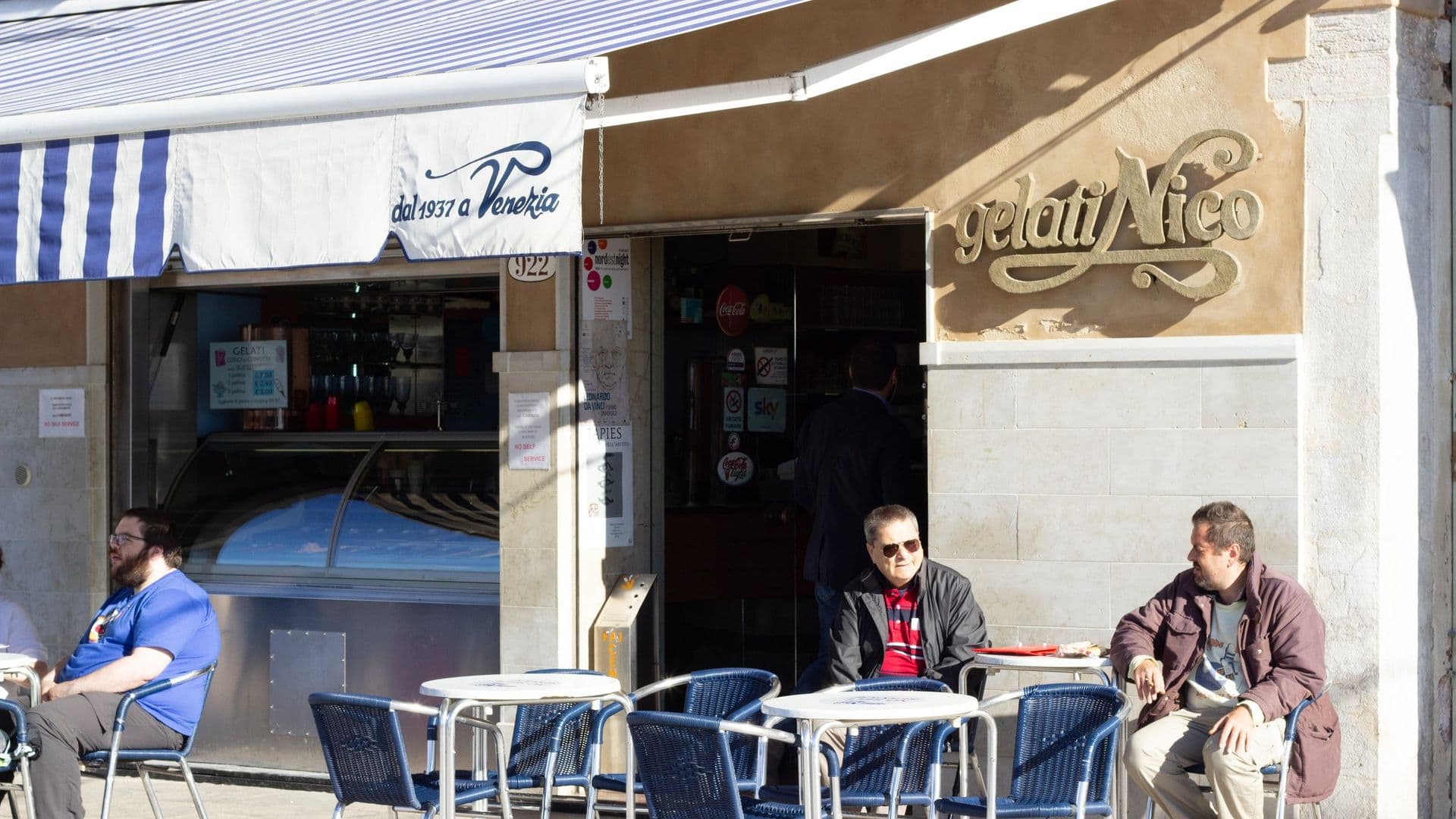Outdoor seating area of an Italian gelato shop "Gelati Nico" with people sitting at tables.