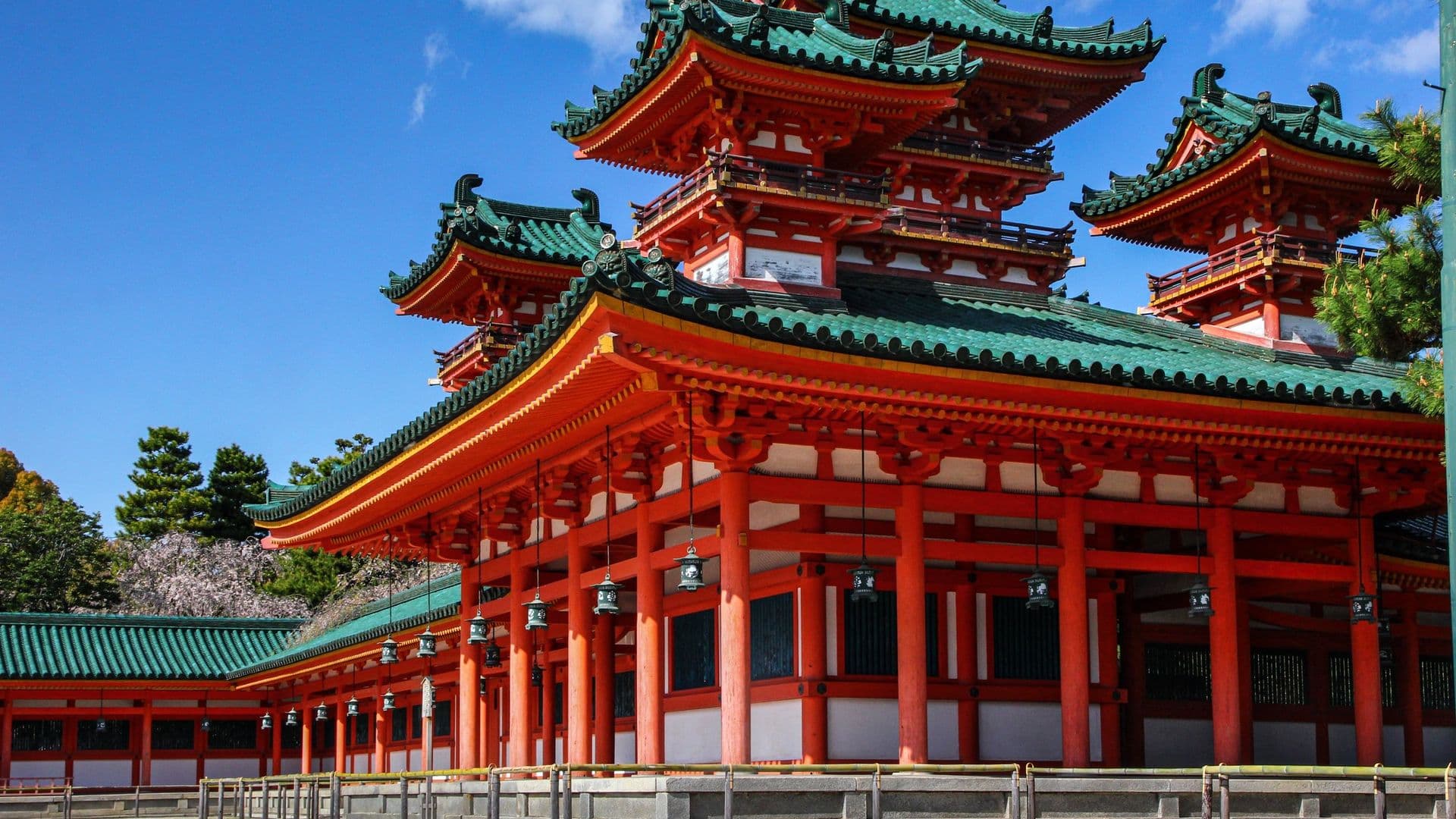 Traditional Japanese temple with red and green pagoda roofs against a blue sky.