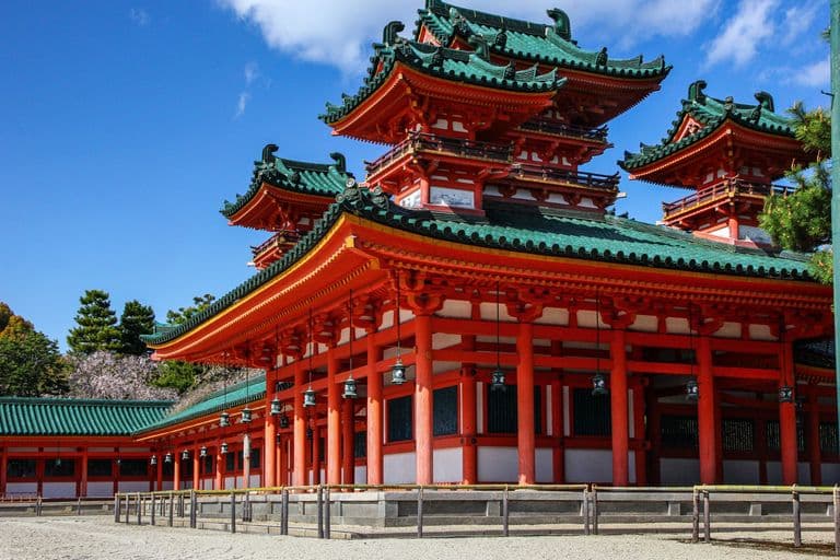 Traditional Japanese temple with red and green pagoda roofs against a blue sky.