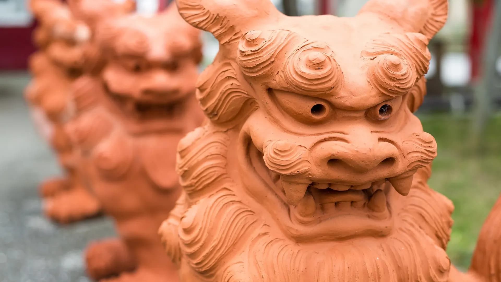 Close-up of terracotta Shisa lion-dog statues in a row