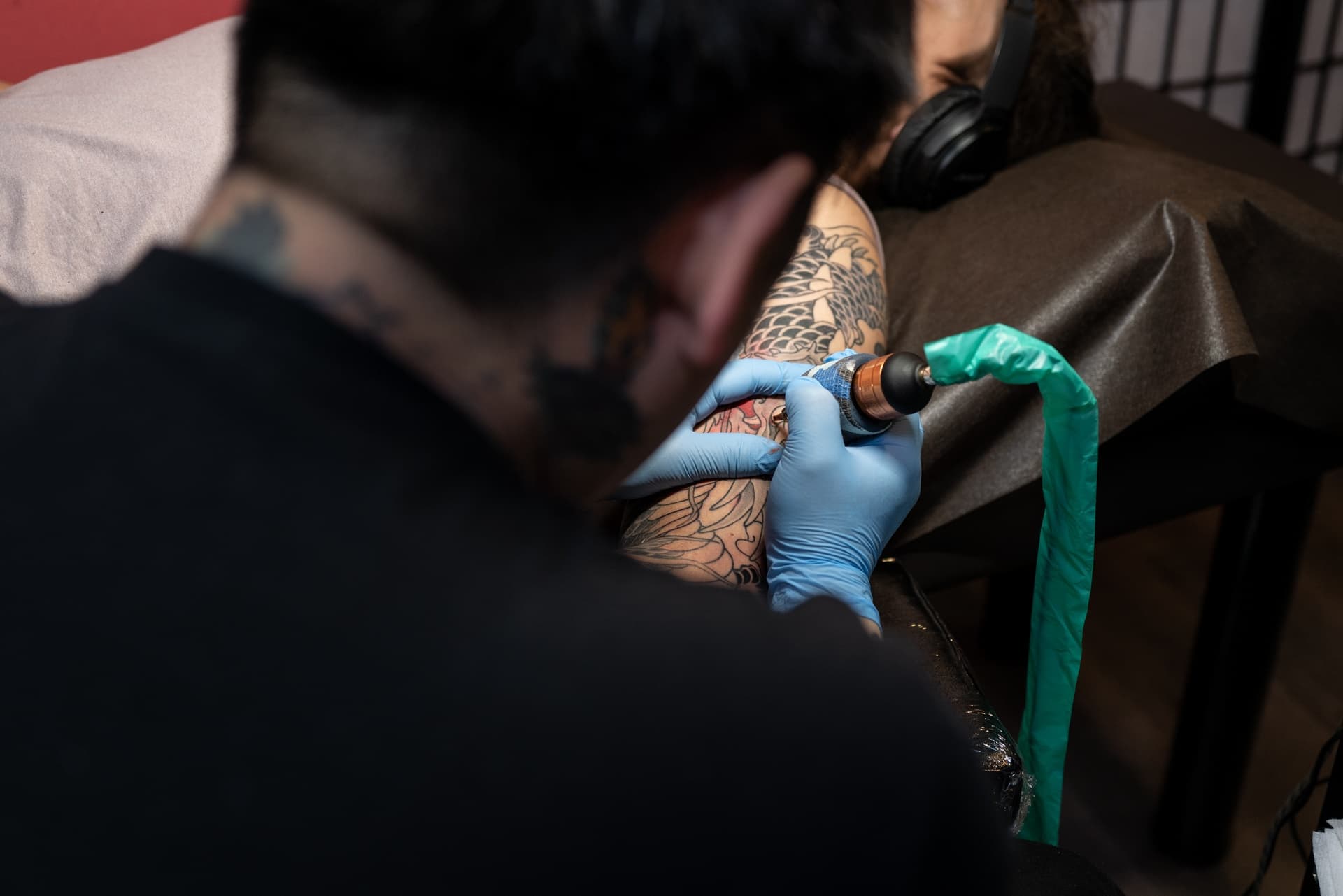 Tattoo artist using a tattoo machine on a client's arm.