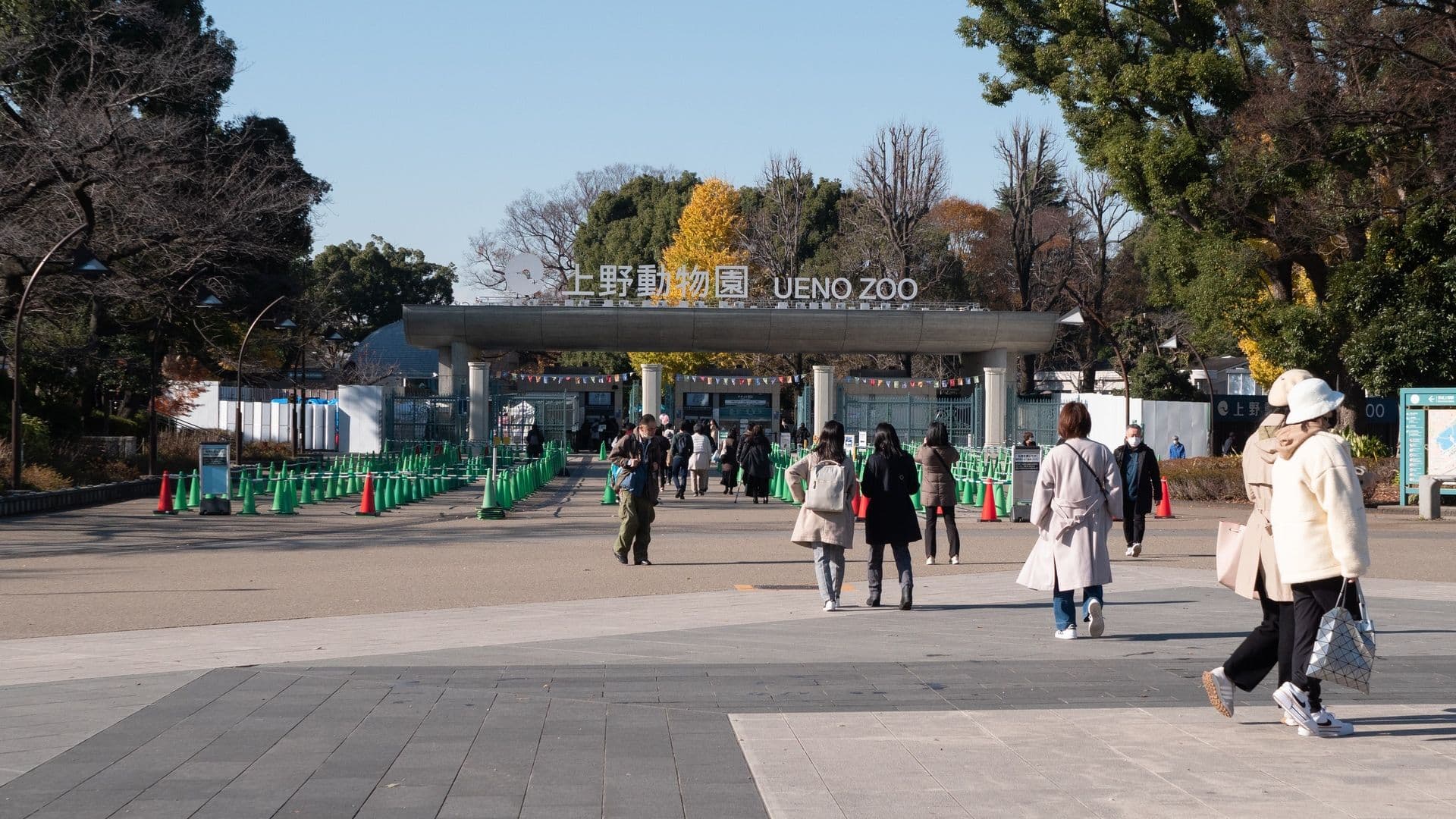Entrance of Ueno Zoo in Tokyo, with people walking towards the gate on a clear day.
