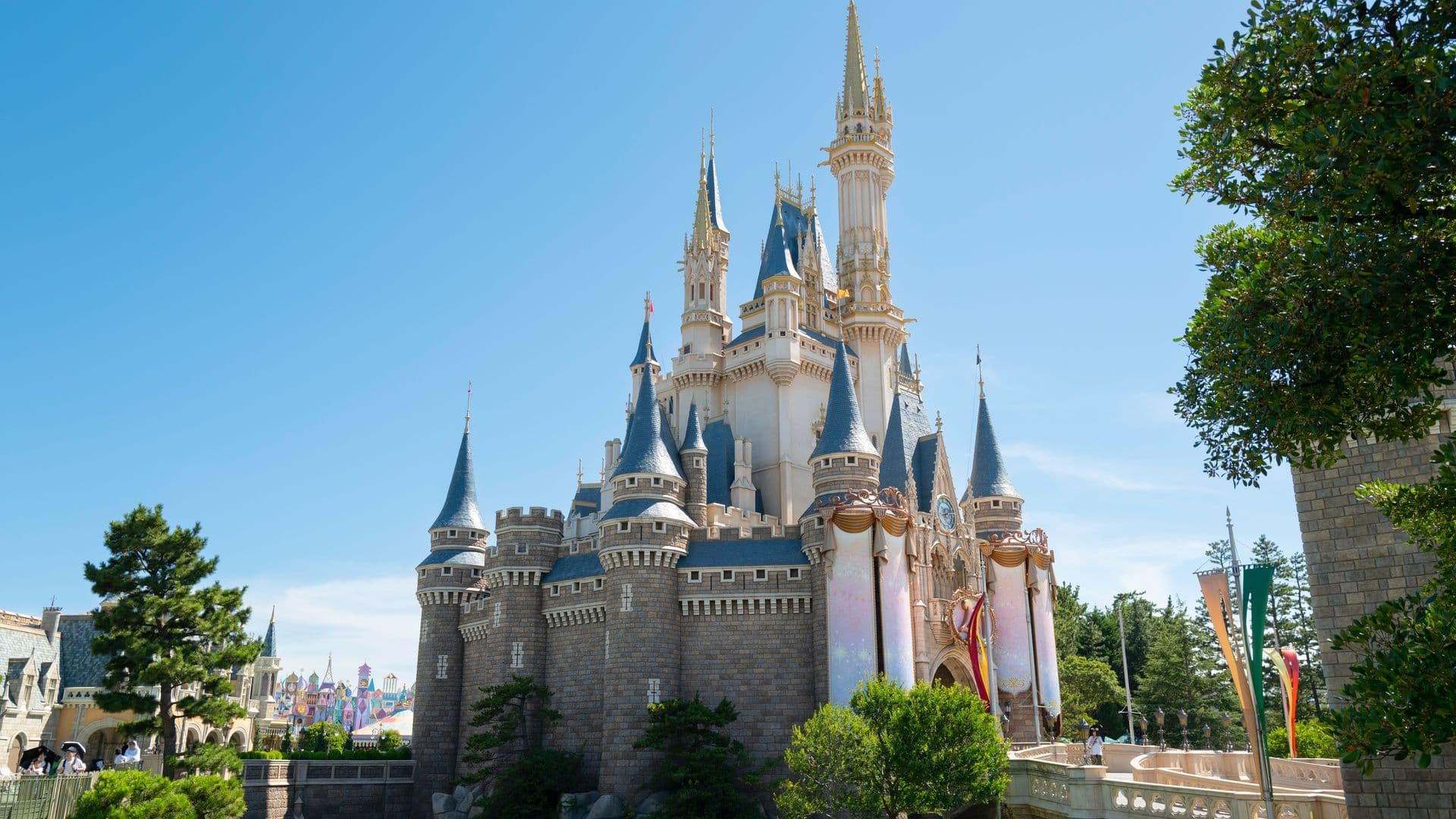 Sleeping Beauty Castle at Disneyland with bright blue sky and green trees.
