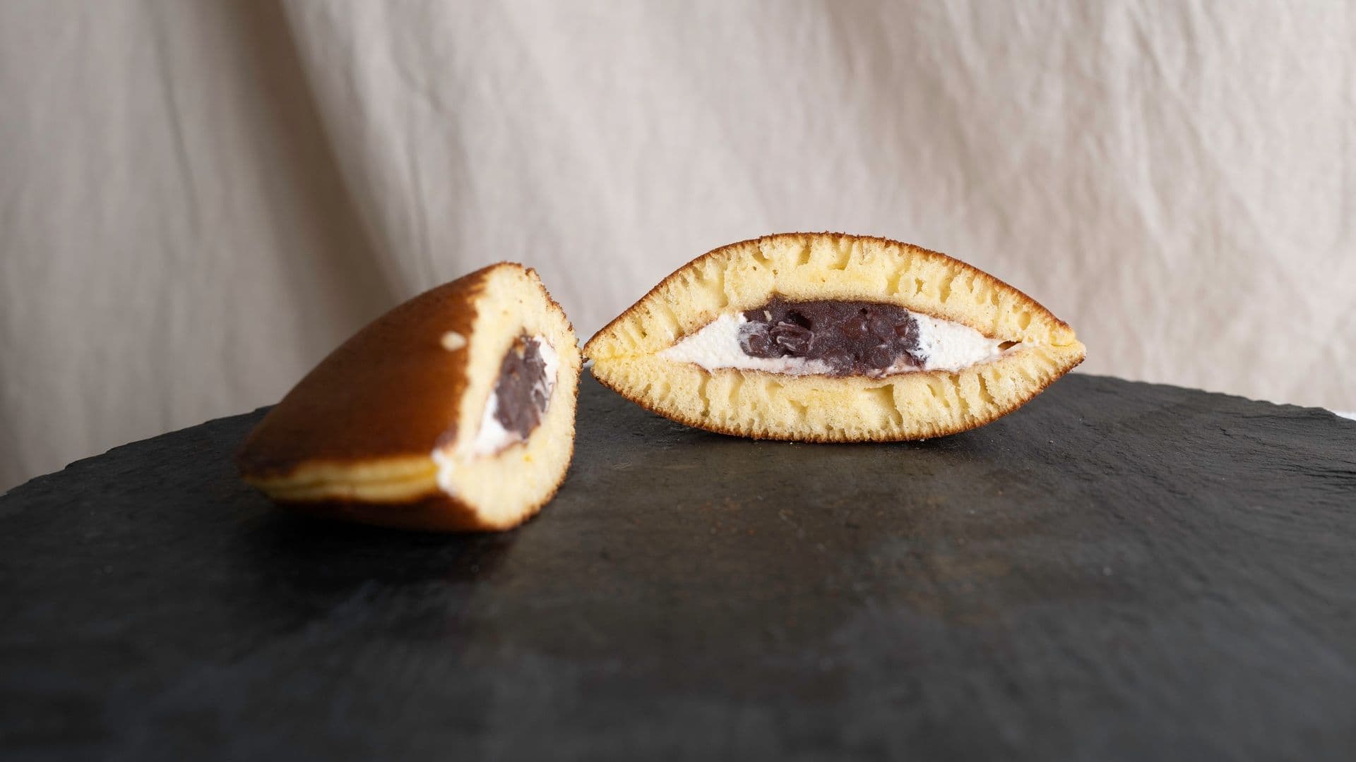 A taiyaki, a fish-shaped Japanese pastry filled with sweet red bean paste, depicted in a cross-section showing the filling.