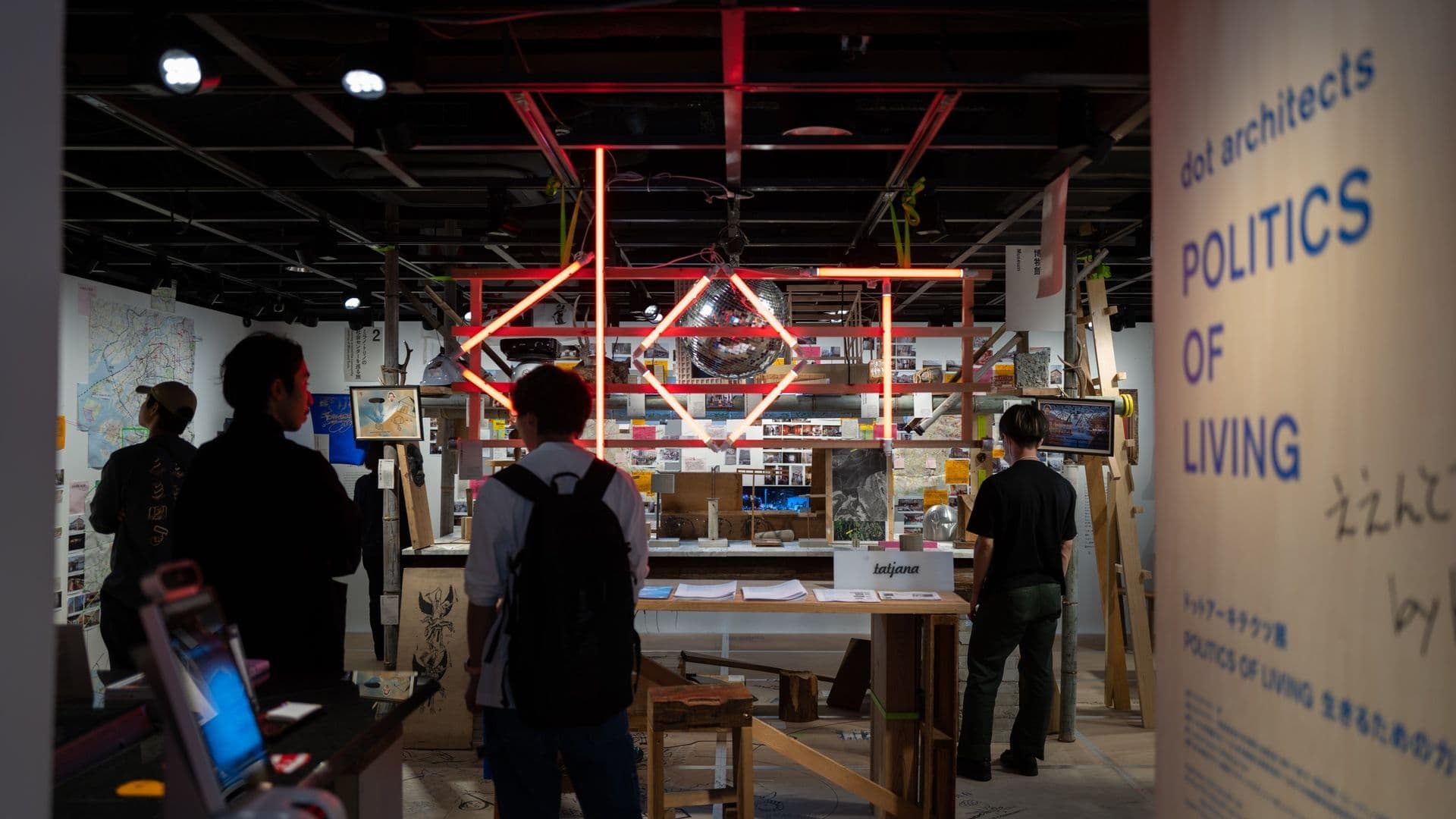 People exploring an art installation with neon lights and various displays inside an exhibition space or museum.