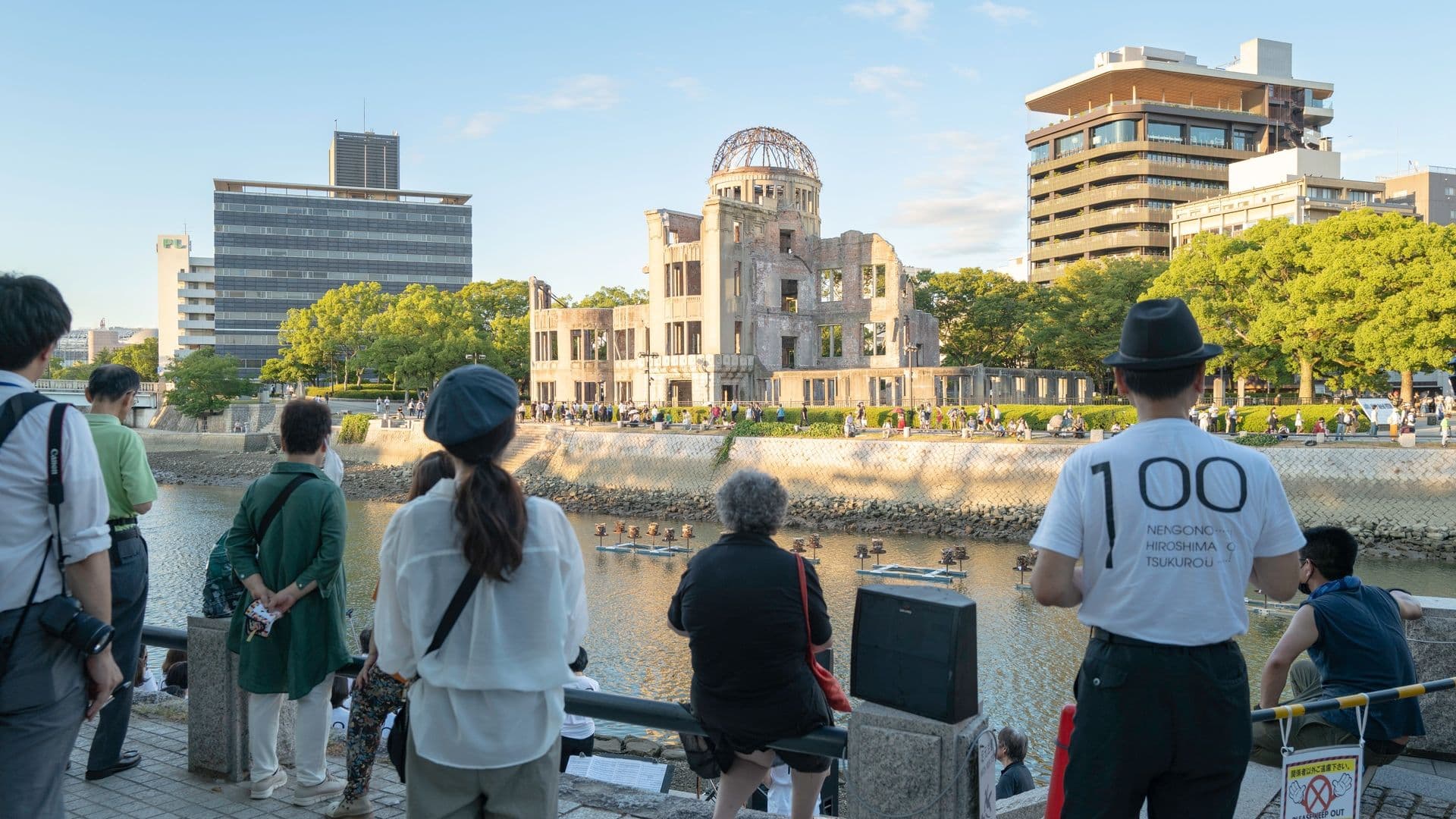 People viewing the Hiroshima Peace Memorial, also known as the Atomic Bomb Dome, along a river in Hiroshima, Japan, during late afternoon.