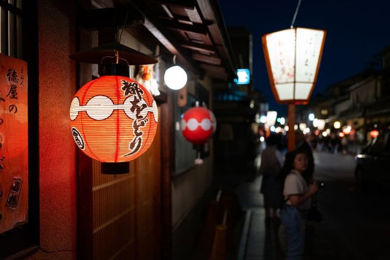 Red paper lanterns hanging outside Japanese restaurant at night with street scene in background