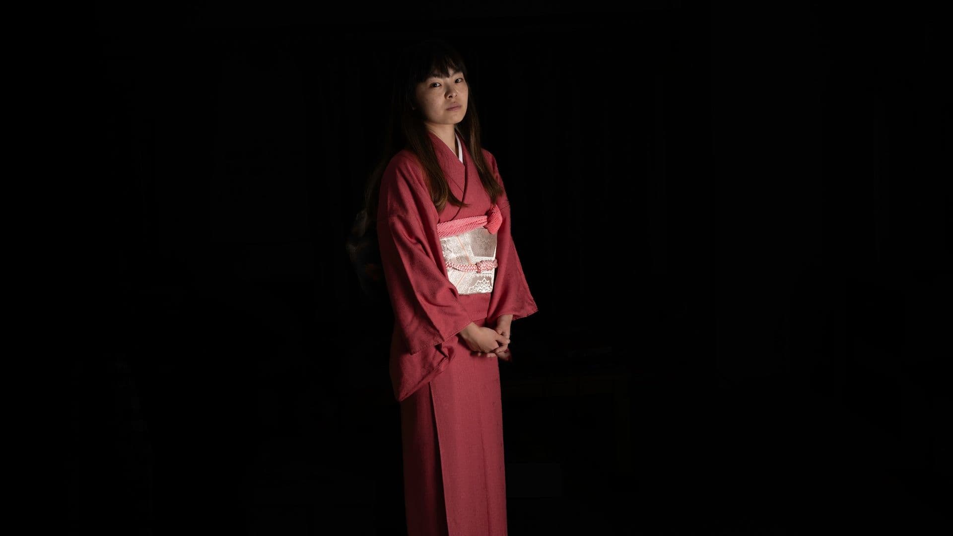 Woman wearing a traditional kimono in a dimly lit room.